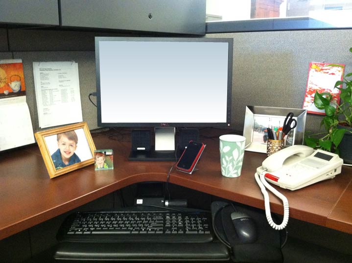 A desk with a computer monitor, smartphone, and various other personal items