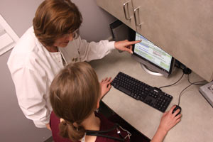 A nurse pointing something out on a computer to a student